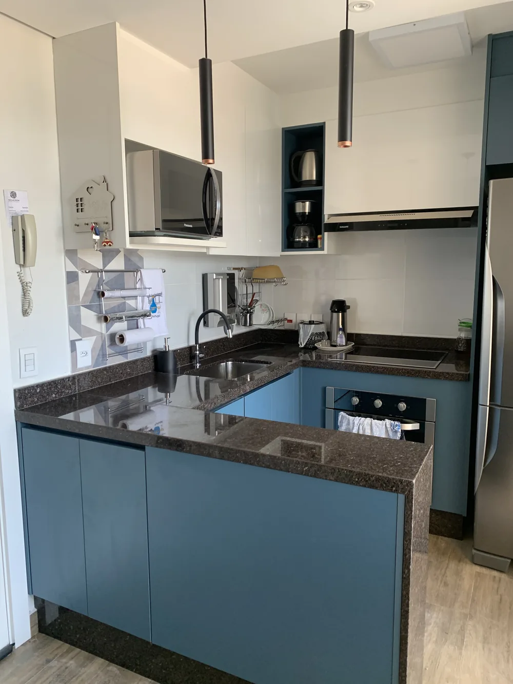 Cozinha planejada em azul petróleo com bancada de granito, projeto Kidar