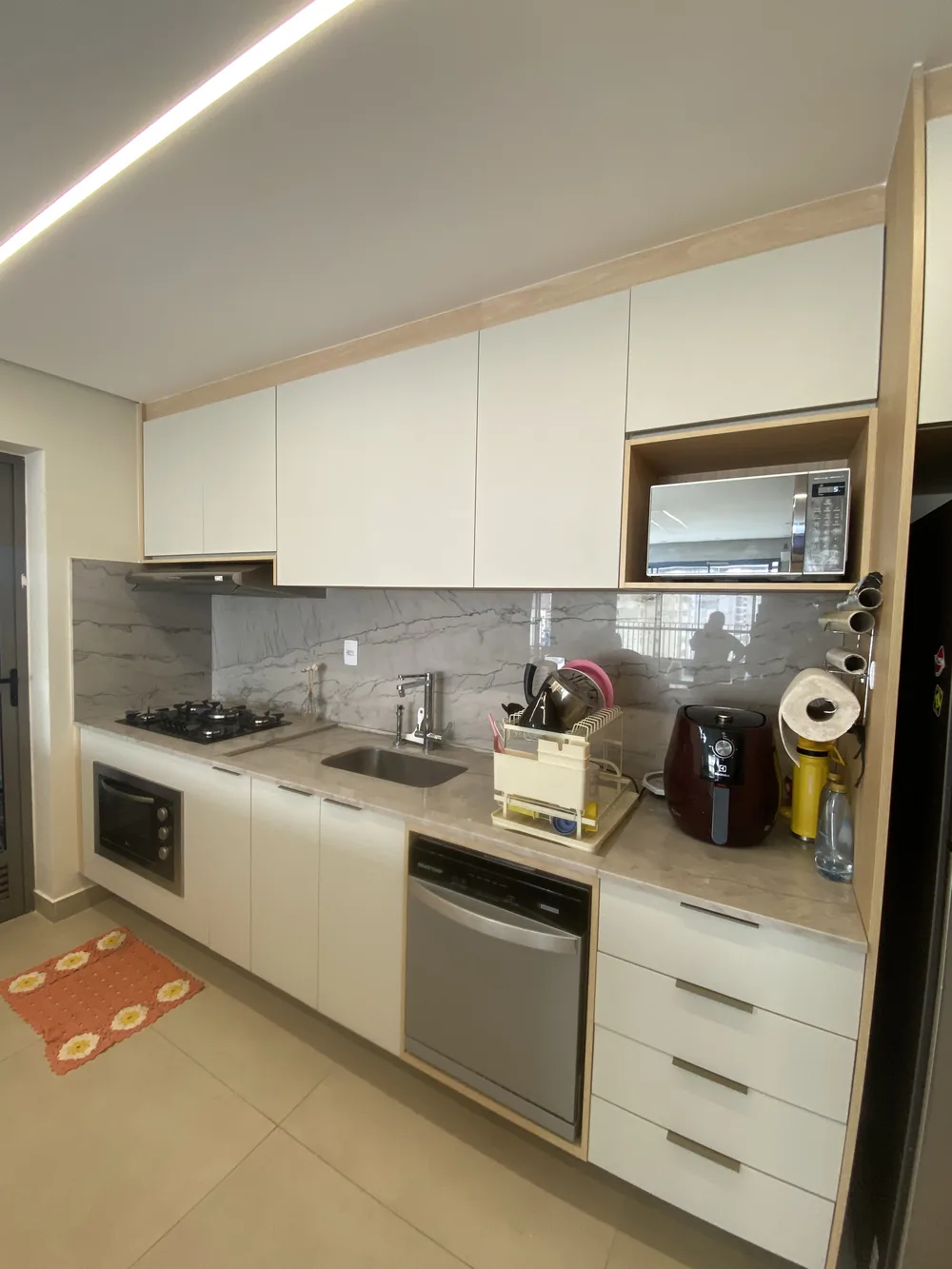 Cozinha planejada branca com bancada em mármore claro, projeto Kidar