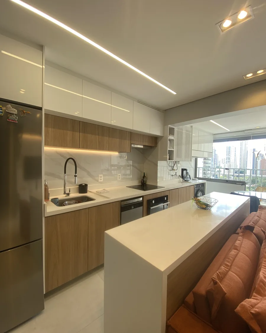 Cozinha planejada da Kidar integrada à sala de estar, com iluminação embutida e vista para a cidade
